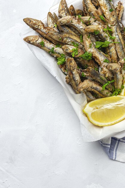 Acciughe fritte tradizionali con limone e prezzemolo. Concetto di frutti di mare