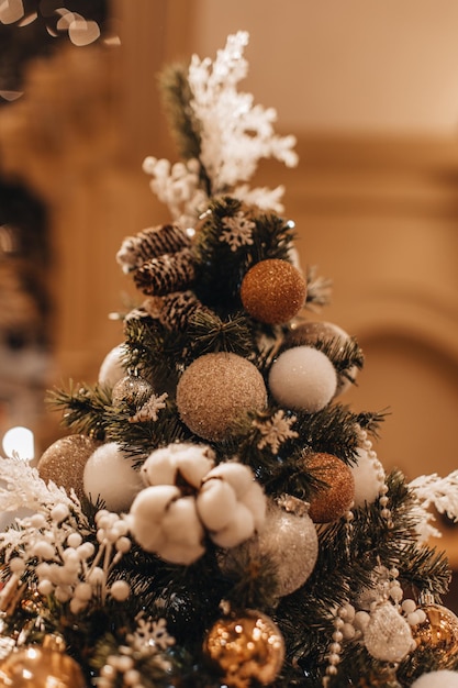 Accogliente albero di Natale decorato con palline di Natale e cotone bianco Dettagli fata bokeh dorato lucido