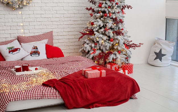 Accogliente camera da letto decorata per le vacanze di Natale con albero e regali