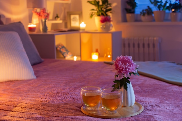 Accogliente camera da letto la sera con fiori e tè