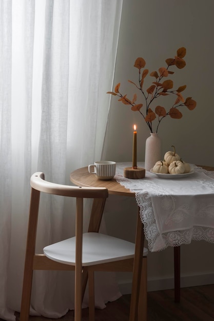 Accogliente casa autunnale Candela con decorazioni autunnali su un tavolo rotondo di legno nel soggiorno