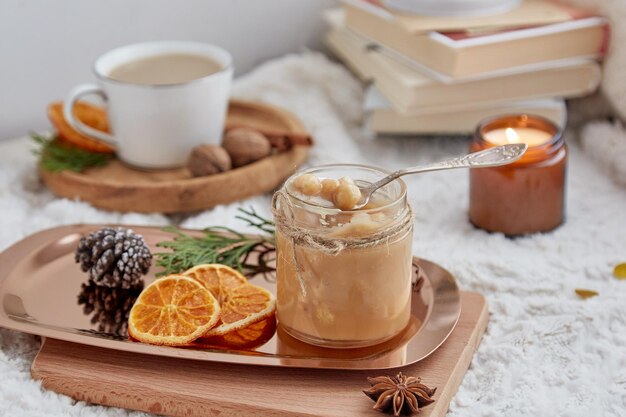 Accogliente colazione natalizia Caramello salato alla nocciola fatto in casa spalmato in barattolo di vetro candele libri e tazza di caffè