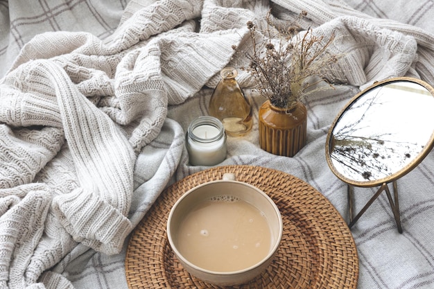 Accogliente composizione autunnale con una tazza di caffè e candele a letto