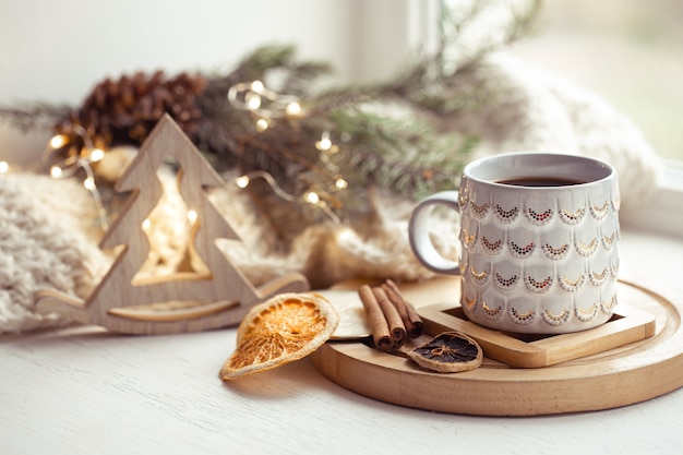 Accogliente composizione con una tazza di Natale con una bevanda calda e cannella su uno sfondo sfocato. Home concetto di intimità invernale.