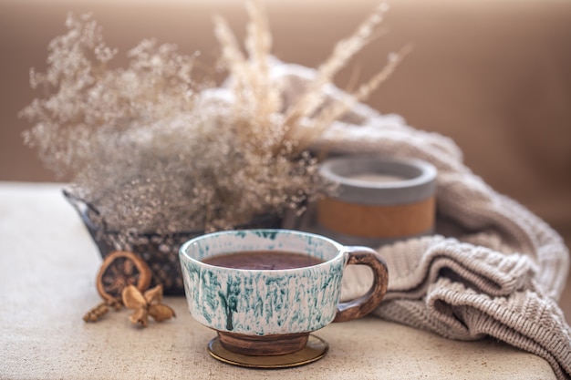 Accogliente composizione domestica con una bella tazza di tè in ceramica sul tavolo. Oggetti decorativi all'interno.