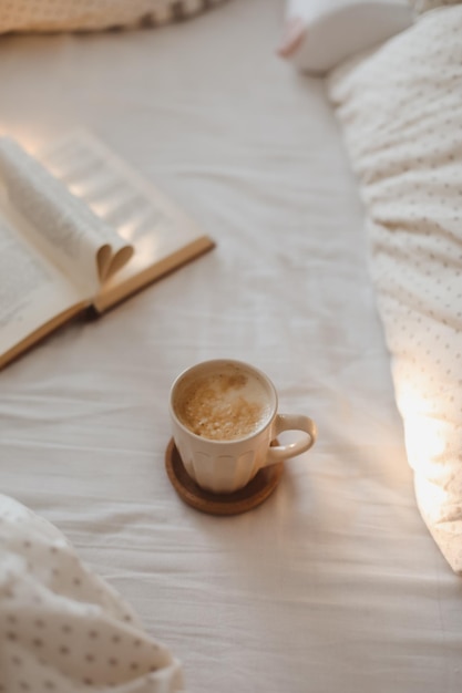 Accogliente composizione mattutina con una tazza di caffè e un libro con pagine piegate a forma di cuore a letto