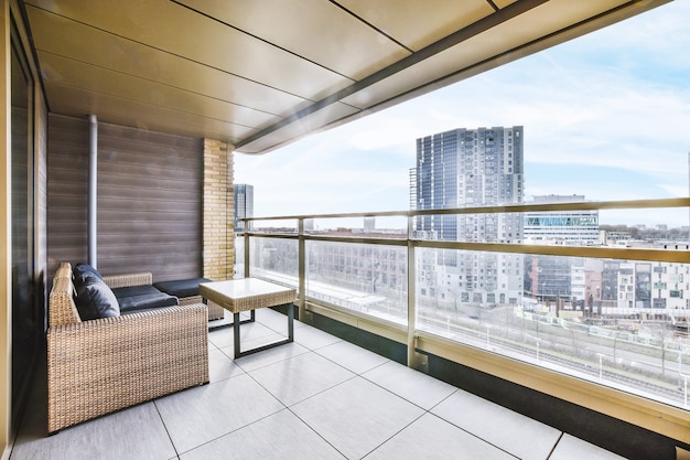 Accogliente divano e tavolo in legno posto sul balcone del condominio con vista sul paesaggio urbano