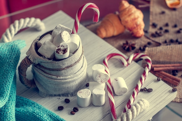 Accogliente natura morta invernale, composta da, tazza di caffè con marshmallow, cornetti e lecca-lecca a strisce