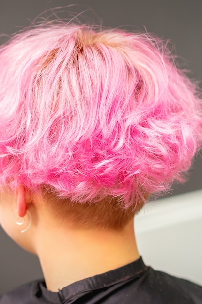 Acconciatura rosa di giovane donna dopo aver colorato i capelli con riflessi nel salone di bellezza