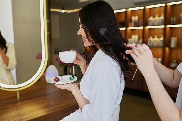 Acconciatura sposa Un parrucchiere femminile fa lo styling dei capelli per la bella giovane donna caucasica in un salone di bellezza