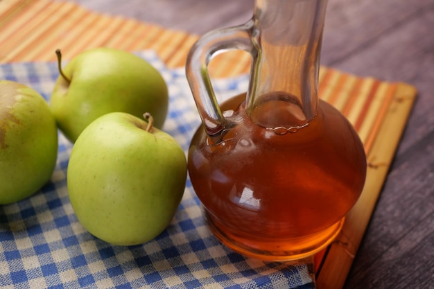Aceto di mele in bottiglia di vetro con mela verde fresca sul tavolo