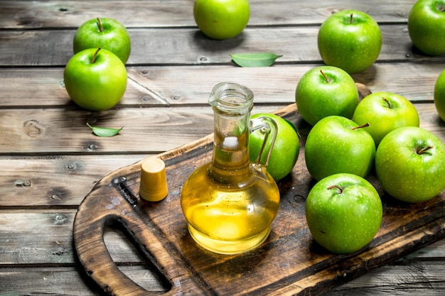 Aceto di sidro di mele con mele verdi su una vecchia tavola