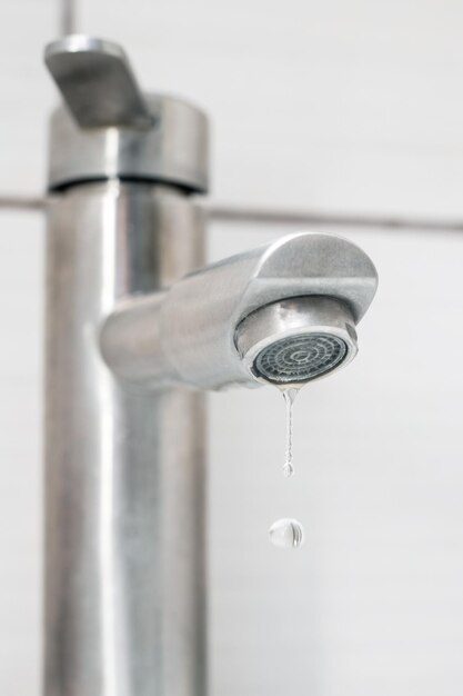 Acqua che gocciola dal rubinetto del bagno Primo piano del rubinetto dell'acqua Risparmio idrico