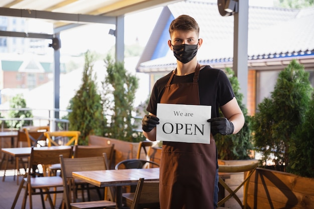 Acqua che lavora con maschera facciale nel ristorante, focolaio di coronavirus