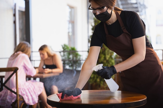 Acqua che lavora con maschera facciale nel ristorante, focolaio di coronavirus