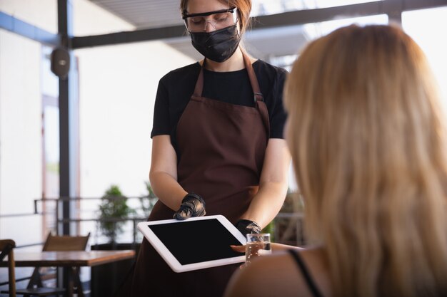 Acqua che lavora con maschera facciale nel ristorante, focolaio di coronavirus