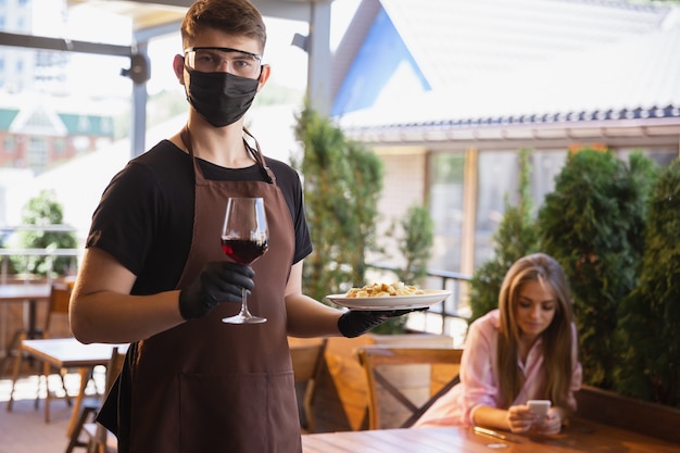 Acqua che lavora con maschera facciale nel ristorante, focolaio di coronavirus