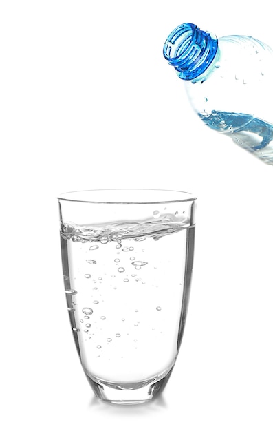 Acqua che si versa dalla bottiglia nel bicchiere su sfondo bianco