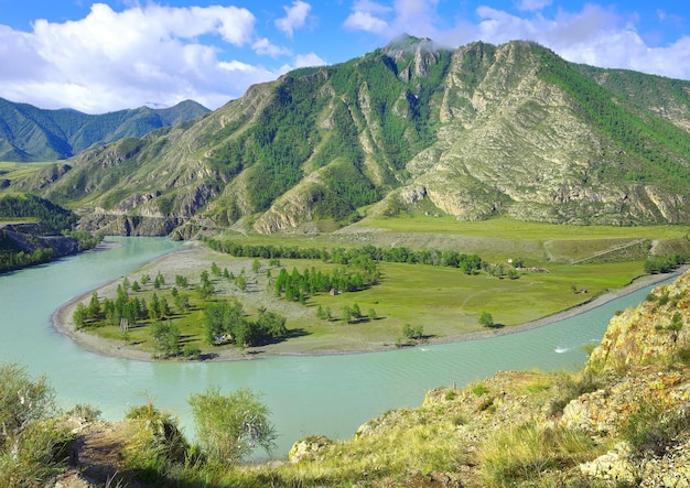 Acqua color smeraldo all'ansa di un fiume di montagna tra le montagne rocciose sotto un cielo blu Siberia