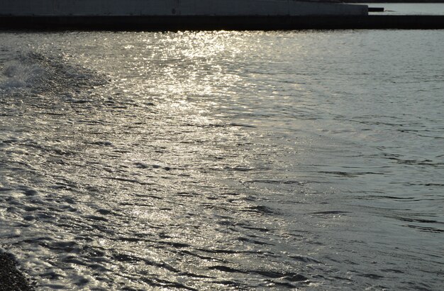 Acqua d&#39;argento lucida sulla spiaggia di ciottoli di mare, all&#39;alba del primo mattino