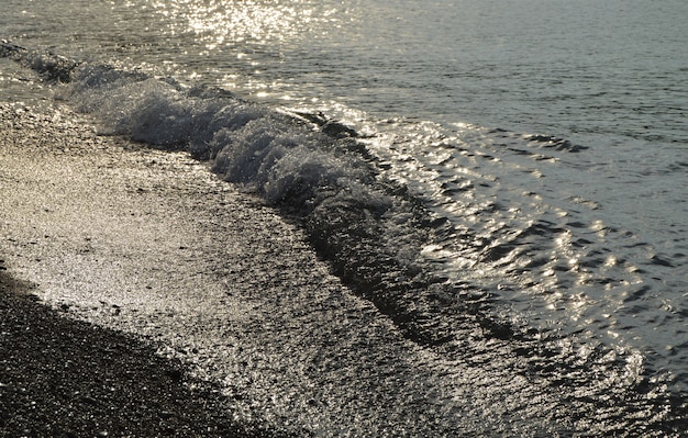 Acqua d&#39;argento lucida sulla spiaggia di ciottoli di mare, all&#39;alba del primo mattino