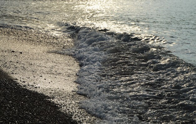 Acqua d&#39;argento lucida sulla spiaggia di ciottoli di mare, all&#39;alba del primo mattino