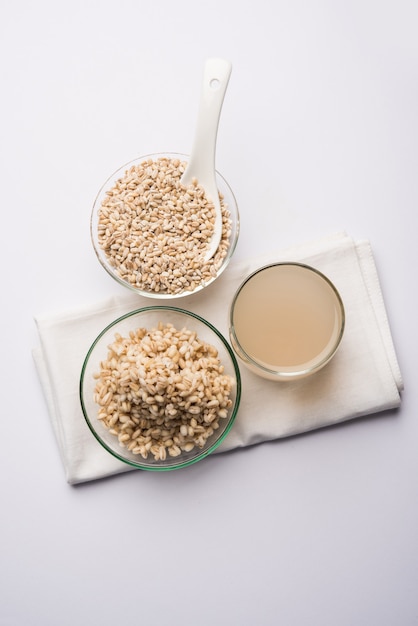 Acqua d'orzo in bicchiere con grano o semi di orzo perlato crudo e cotto. messa a fuoco selettiva