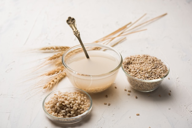 Acqua d'orzo in bicchiere con grano o semi di orzo perlato crudo e cotto. messa a fuoco selettiva