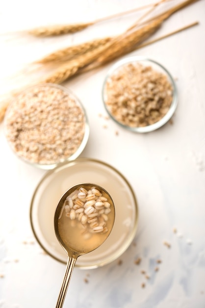 Acqua d'orzo in bicchiere con grano o semi di orzo perlato crudo e cotto. messa a fuoco selettiva