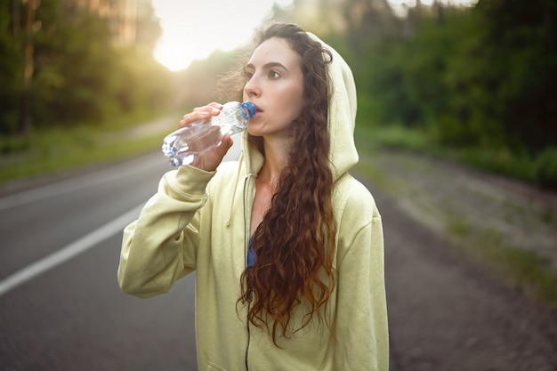 Acqua della bevanda dell'atleta della donna all'aperto