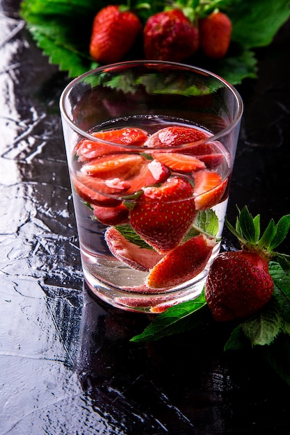 Acqua della disintossicazione della menta della fragola in vetro sul nero. Dieta. Avvicinamento.