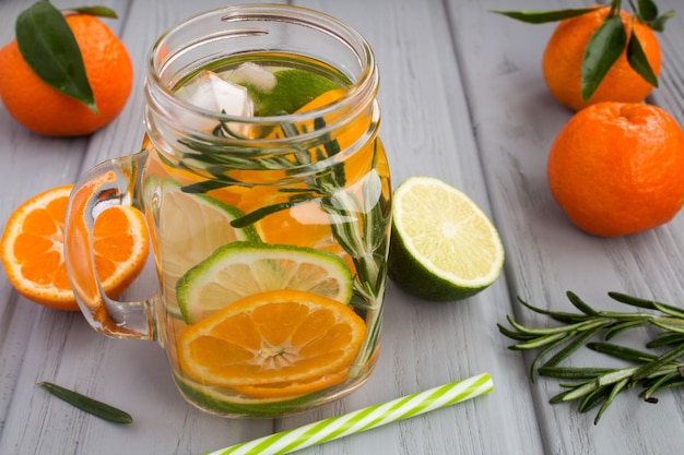 Acqua detox con mandarini, lime e rosmarino su fondo di legno grigio