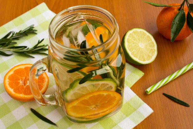 Acqua detox con mandarini, lime e rosmarino sul tovagliolo verde