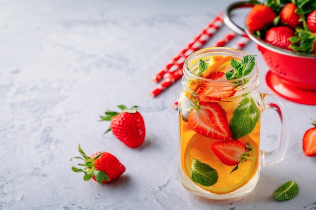 Acqua detox infusa con fragola arancia e menta Cocktail estivo ghiacciato o limonata in barattolo di vetro