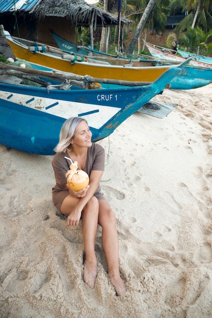 Acqua di cocco bionda della bevanda della donna sulla barca di legno