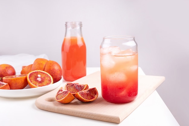 Acqua di frutta in un bicchiere con cubetti di ghiaccio, limonata all'arancia rossa, bevanda rinfrescante estiva