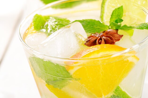 Acqua di frutta lime e arancia con ghiaccio e menta su tavola bianca