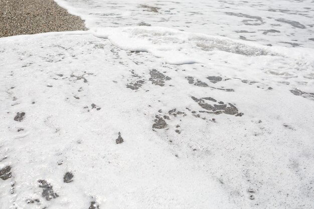 Acqua di mare da un'onda con schiuma in riva al mare