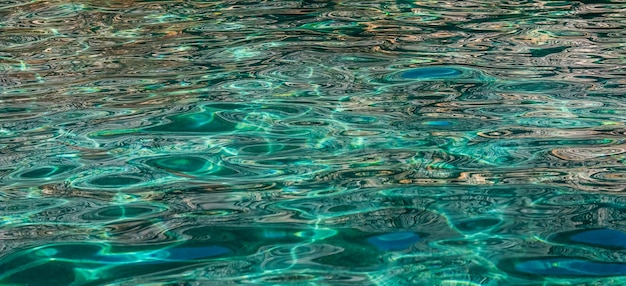 Acqua di mare smeraldo al sole che brilla come sfondo della superficie Concetto di vacanze estive