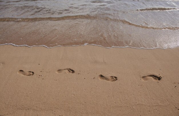 Acqua di mare tropicale proveniente sulla spiaggia di sabbia bianca con impronta.