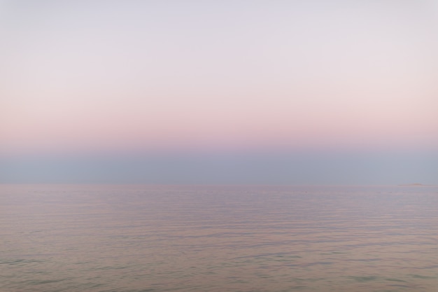 Acqua e cielo pacifici del tramonto dell'oceano rosa pastello astratto