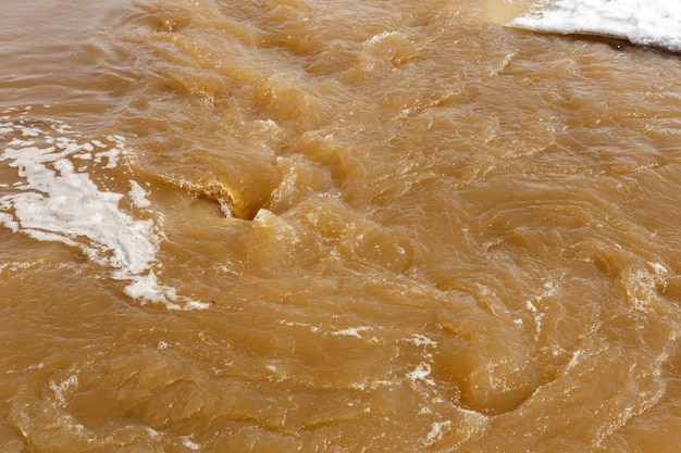 Acqua fangosa di fiume inondazione di primavera sporca acqua fangosa con idromassaggio e schiuma bianca primo piano