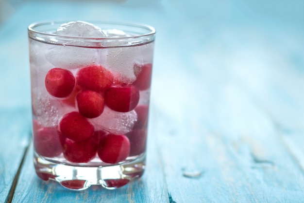 Acqua fredda con ghiaccio, ciliegie e frutti di bosco.