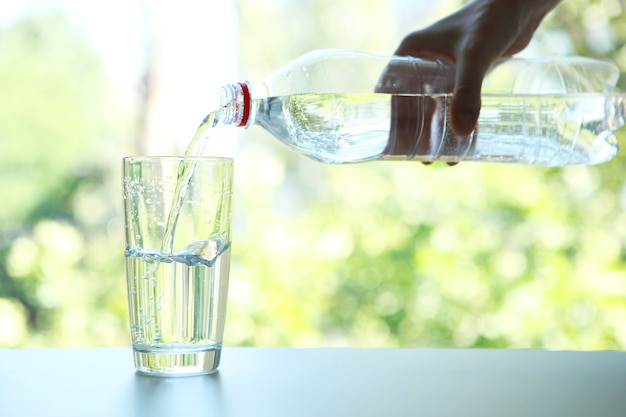 Acqua limpida in un bicchiere e bottiglia sul tavolo