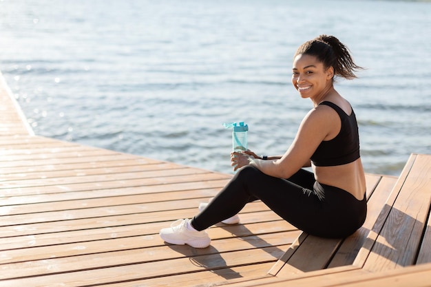 Acqua potabile allegra della donna atletica dell'afroamericano durante l'esercizio