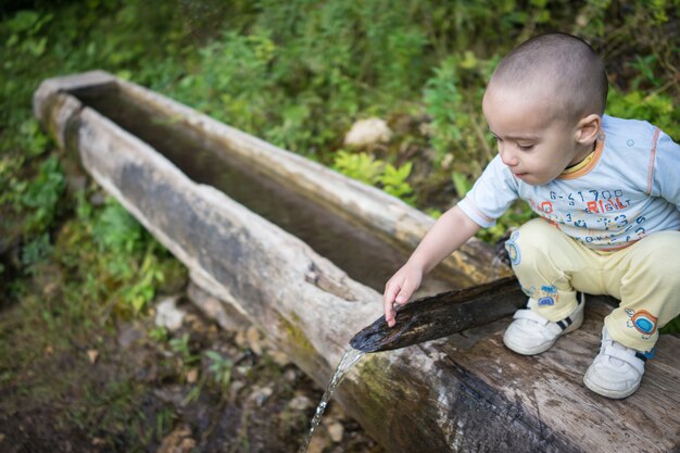 Acqua potabile del bambino sveglio in primavera di montagna