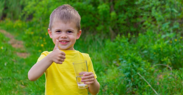 Acqua potabile del ragazzino con un bicchiere nel parco