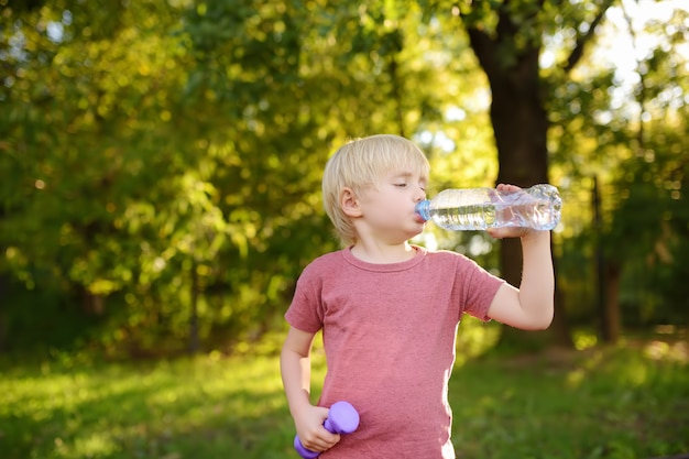 Acqua potabile del ragazzino durante l&#39;allenamento con manubri