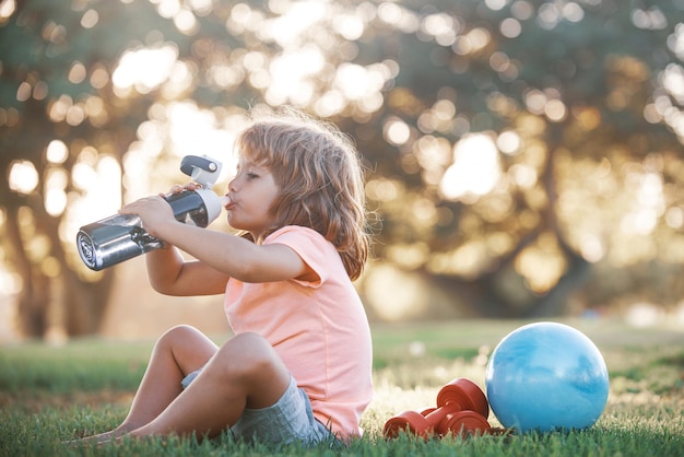 Acqua potabile del ragazzo. Sport Bambino Fitness, salute ed energia, esercizi all'aperto.