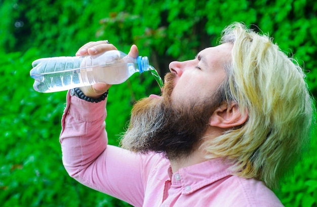 Acqua potabile dell'uomo barbuto. Concetto di idratazione. Ragazzo con bottiglia d'acqua. Uno stile di vita sano.